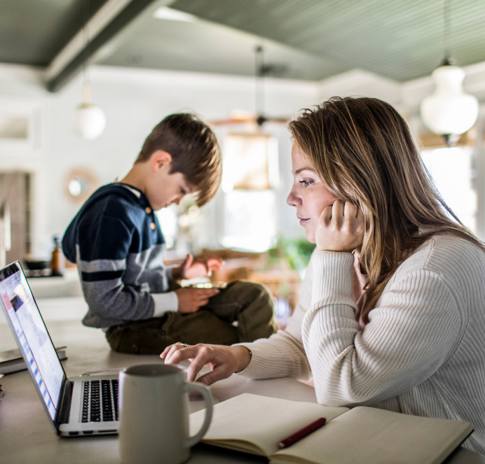 A lady working on laptop with son sitting in background