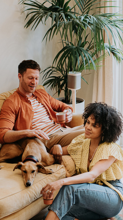 A young couple and their dog sat on a sofa